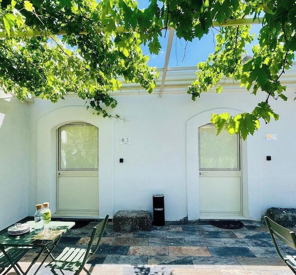 Ein Innenhof mit zwei Rundbögen, einem Tisch mit Stühlen und einer Bank.