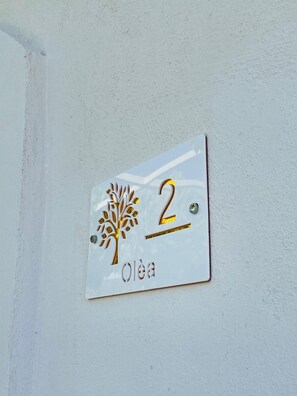 A white wall-mounted sign with a tree logo and the number '2' indicating room number. - Nestled among the rows of orange trees, Zagara Suite is an oasis of peace and relaxation (Francofonte)