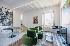 A modern interior with a dining area, green seating, a staircase, and a large window with a view. - Vrbo Property (Arezzo)