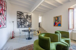 A modern living room with a round glass table, clear chairs, a green sofa, and artwork on the walls. - Palace d'Art - Historic Center of Arezzo (Arezzo)
