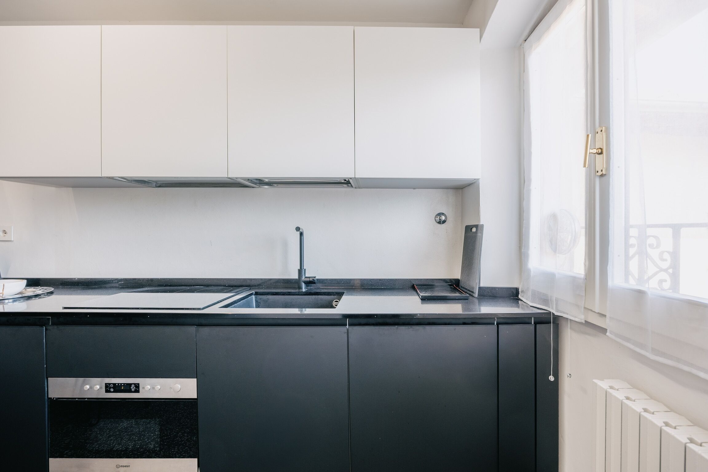 Una cucina moderna con lavello in acciaio inossidabile, mobili neri e forno integrato.
