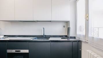 Una cucina moderna con lavello in acciaio inossidabile, mobili neri e forno integrato.