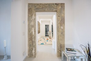 A hallway with a rustic stone archway, leading to a bathroom with a glass shower and a patterned rug. - Palace d'Art - Historic Center of Arezzo (Arezzo)