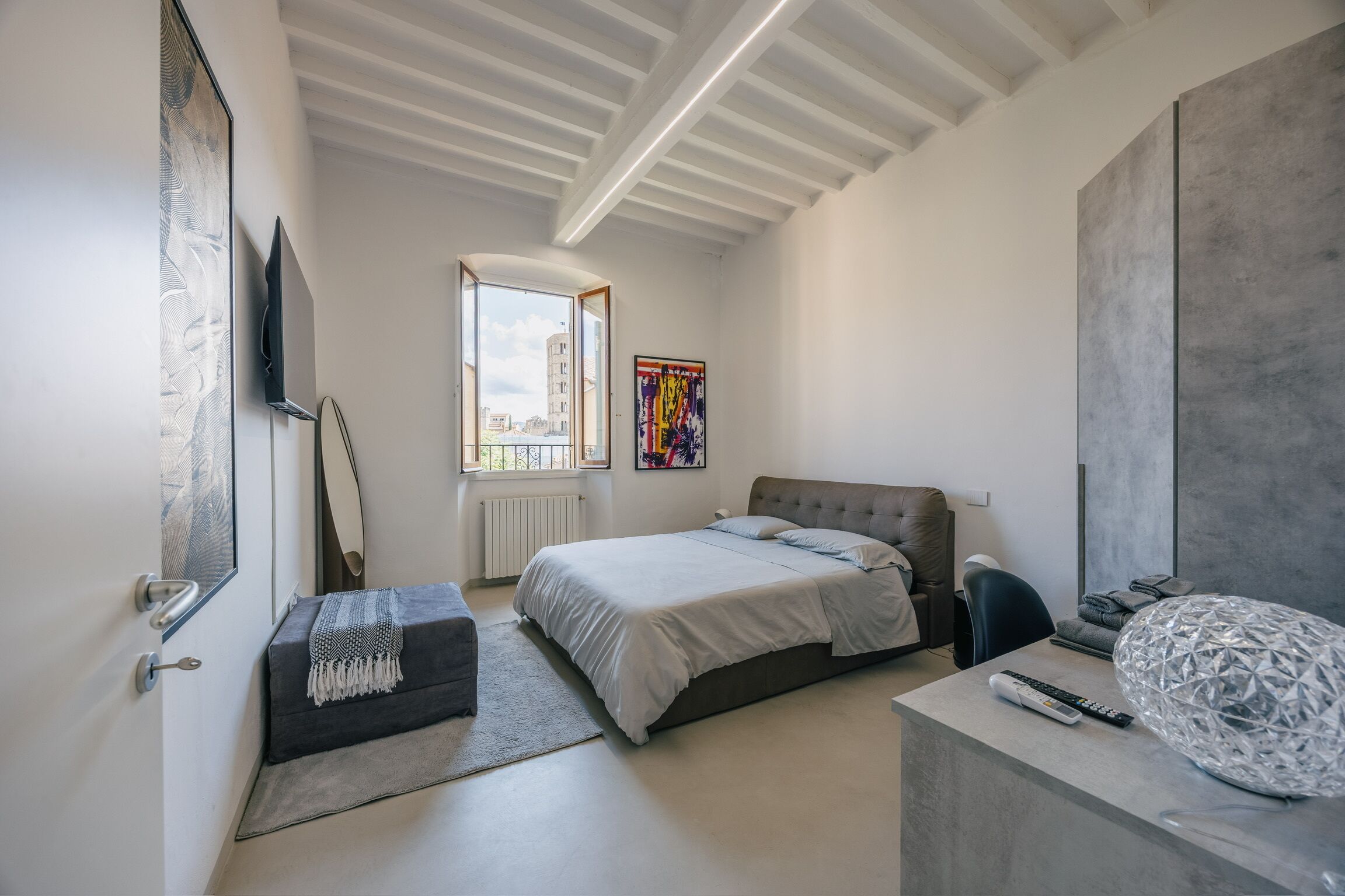 Una camera da letto moderna con un letto, una scrivania, una sedia, una finestra e un quadro.