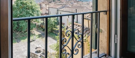 A balcony with a metal railing overlooking a cityscape with historic buildings and a clear sky.