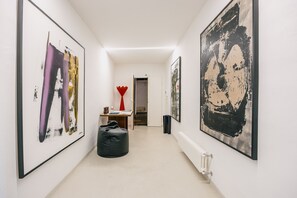 A hallway with large abstract paintings on the walls, a red sculpture, and a black bean bag chair. - Palace d'Art - Historic Center of Arezzo (Arezzo)