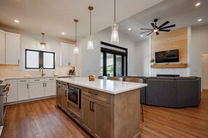 A modern kitchen with a central island, stainless steel appliances, and pendant lighting. - New! Luxurious Lake Access Getaway w/ Indoor Pool (Swanton)