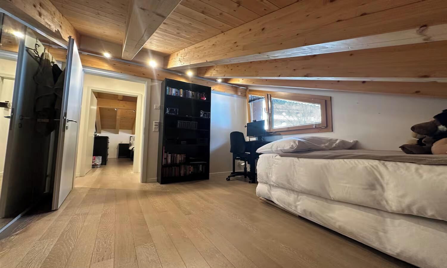 Une chambre à coucher avec un lit, un bureau, une bibliothèque et une armoire.