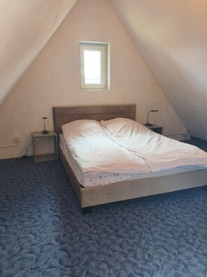 A single bed in a room with a sloped ceiling, a small window, and two bedside tables with lamps. - Tranquil 1-bedroom cottage perfect for a relaxing getaway (Unknown)