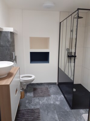 Een moderne badkamer met toilet, wastafel, douchecabine en een vloer van marmer.