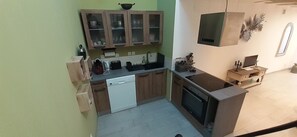 Een compacte keuken met een vaatwasser, een kookplaat en een klein spoelgedeelte.