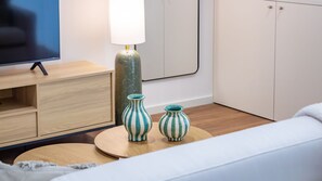 Ein modernes Zimmer mit Fernseher, einer Lampe und zwei gestreiften Vasen auf einem runden Tisch.