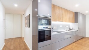 Une cuisine moderne dotée d’un four encastré, d’un évier et de meubles de rangement en bois.