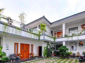 A two-story building with a balcony, potted plants, and a motorcycle. - Nexdeco house homestay syariah (Surakarta)