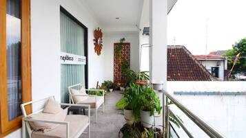 A balcony with a sofa, potted plants, and a sign reading 'nexdec'.