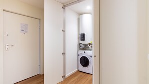 A hotel room with a closed door, a visible notice on the wall, a washing machine, and a water heater. - Polacos Residence | 2BR | Apt O by LovelyStay (Vila Nova de Gaia)