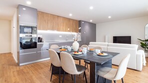 A modern kitchen with built-in appliances, a dining area with a marble table, and a living room with a white sofa. - Polacos Residence | 2BR | Apt O by LovelyStay (Vila Nova de Gaia)