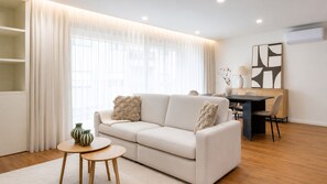 A modern living room with a sofa, a coffee table, and a dining area with a table and chairs. - Polacos Residence | 2BR | Apt O by LovelyStay (Vila Nova de Gaia)