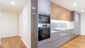 A modern kitchen with a built-in oven, a sink, and wooden cabinetry. - Polacos Residence | 2BR | Apt O by LovelyStay (Vila Nova de Gaia)