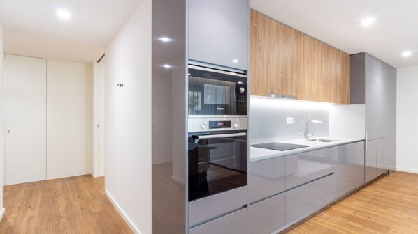 A modern kitchen with a built-in oven, a sink, and wooden cabinetry. - Polacos Residence | 2BR | Apt O by LovelyStay (Vila Nova de Gaia)