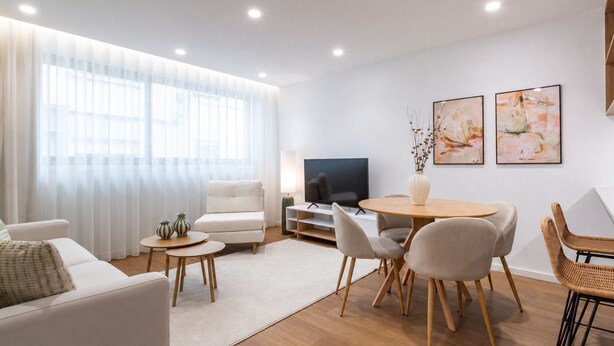 Ein modernes Wohnzimmer mit Sofa, Couchtisch, Fernseher und Essbereich.