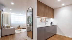 Un appartement moderne comprenant un espace de vie, une cuisine avec des meubles en bois et un grand miroir.