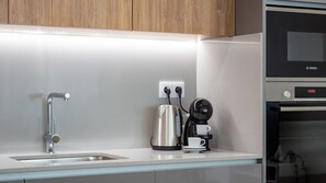 Cozinha moderna com pia de aço inoxidável, chaleira, cafeteira e forno Bosch.