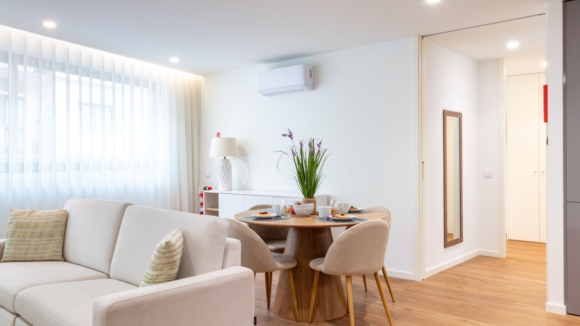 Un salon moderne avec un canapé, une table à manger et des chaises, ainsi qu’une plante en pot.