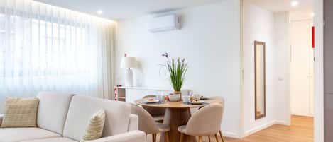 Un salon moderne avec un canapé, une table à manger et des chaises, ainsi qu’une plante en pot.