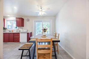Eine moderne Küche mit Essbereich, ausgestattet mit einem Holztisch, Stühlen und einer Bank, sowie einem Deckenventilator.