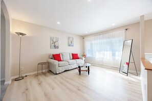 A modern living room with a sofa, a coffee table, and a floor lamp. - Spacious 4BR House|15 Min to DT|DIX30|3 Parking| Central AC (Brossard)