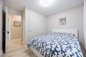 A bedroom with a bed, a door, a painting, and a hallway. - Spacious 4BR House|15 Min to DT|DIX30|3 Parking| Central AC (Brossard)