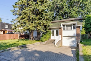 A residential house with a brick facade, a front porch, and a garage. - Spacious 4BR House|15 Min to DT|DIX30|3 Parking| Central AC (Brossard)
