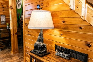 L’intérieur d’un chalet en bois, avec une lampe sur une table, une pancarte « BIENVENUE » et une pancarte « CHALET ».