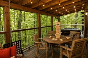 Een terras van hout met een tafel en stoelen, omgeven door een houten hek, en een jacuzzi op de achtergrond.