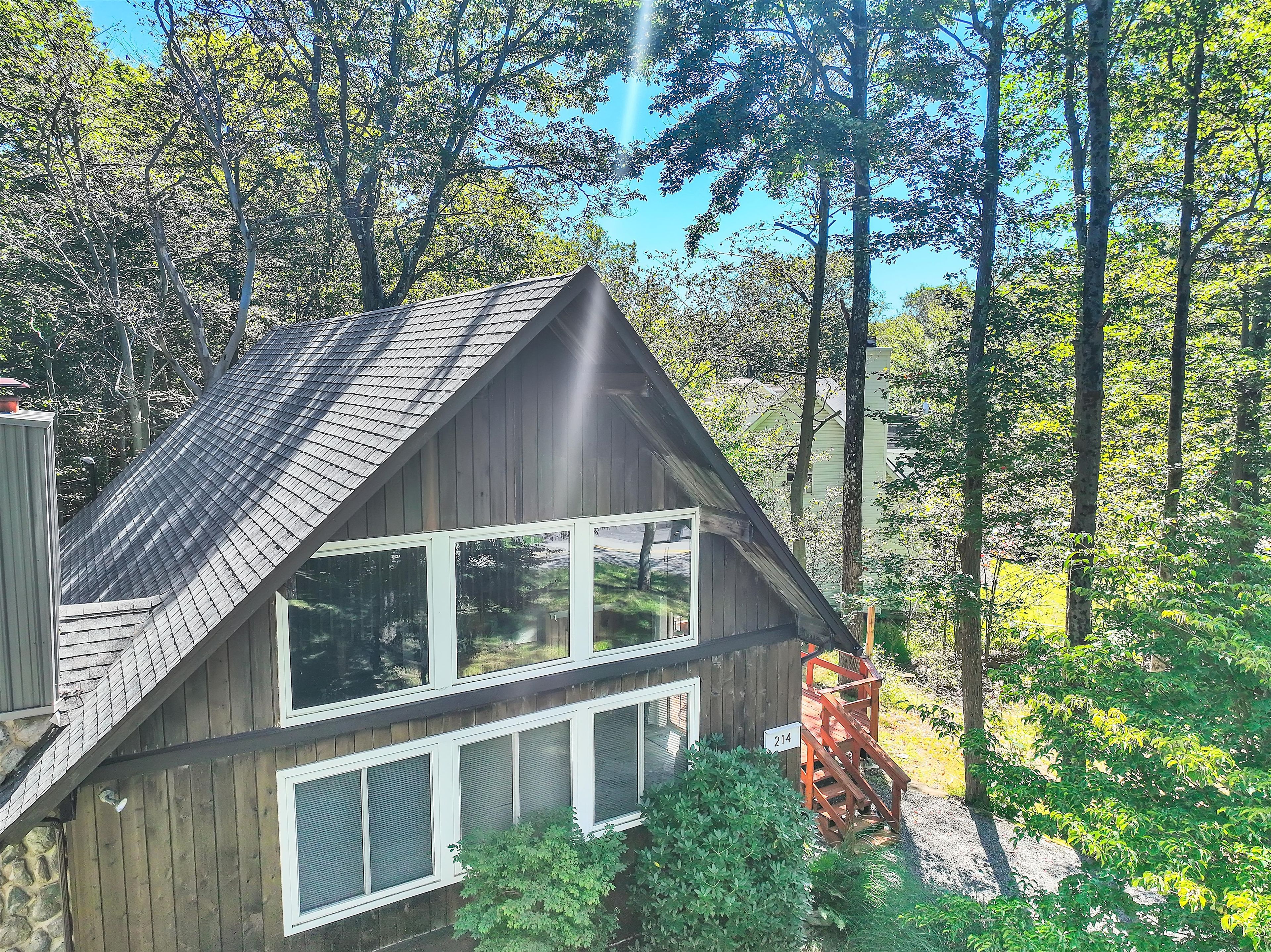 A wooden cabin with a steeply pitched roof, large windows, and a number '214' sign.