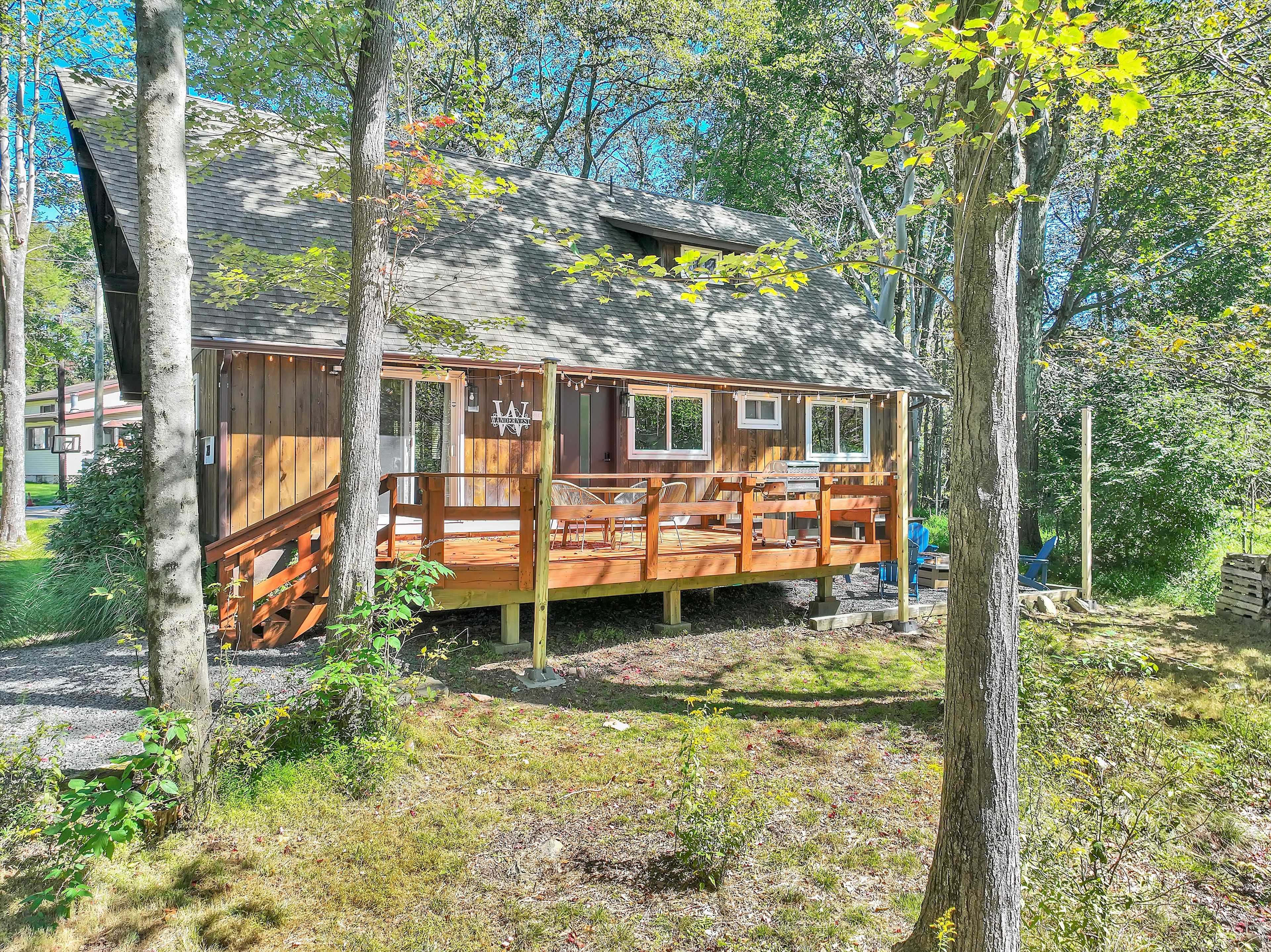 A wooden cabin with a deck, surrounded by trees.
