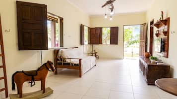 Um quarto com uma cama, um balanço de madeira, uma escrivaninha e uma televisão.