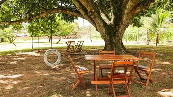 A wooden table and chairs set under a large tree in a park.