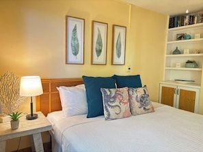 A bedroom with a bed, a bedside table with a lamp, and a bookshelf. - *Hono Kai A16* New Listing! New remodel! Maui condo steps to the sand! (Maalaea)