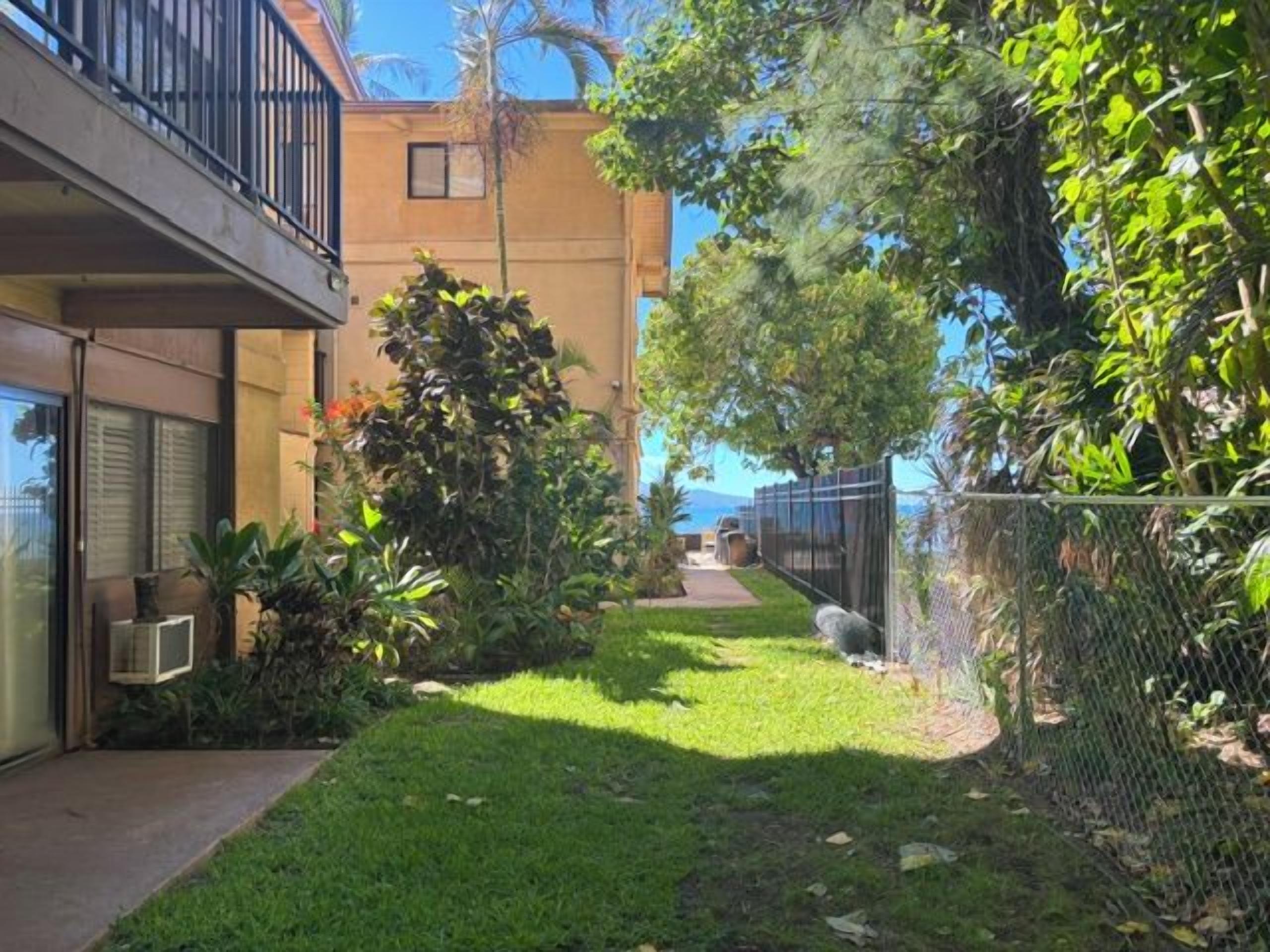 A residential area with a grassy lawn, a pathway, and a building with a balcony.
