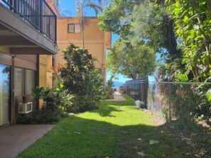 Ett bostadsområde med en gräsyta, en gångstig och en byggnad med en balkong.