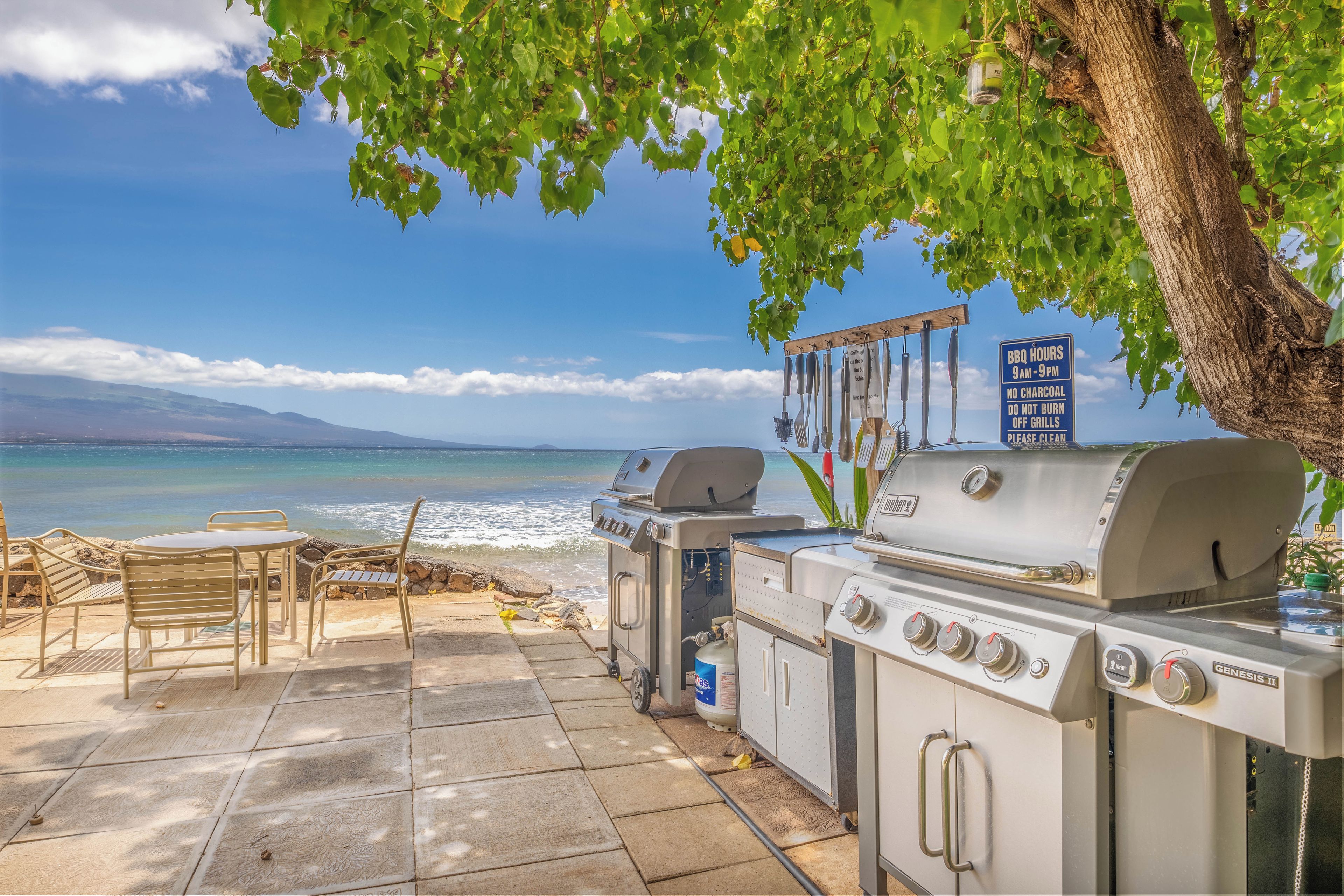 An outdoor patio with a grill and seating area overlooking a beach.
