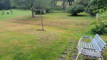 A grassy outdoor area with a metal bench and a wooden swing set.