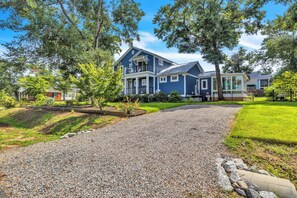 A two-story house with a gravel driveway leading to the entrance. - Blue Lagoon: Gorgeous Home Near Waterway with Private Pool (Oak Island)