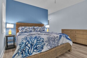 Een slaapkamer met een bed, twee bedlampen, een nachtkastje, een houten dressoir en een blauwe wand.