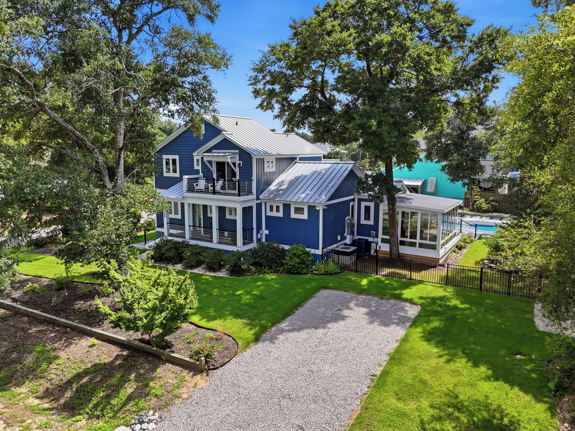A two-story house with a balcony, a swimming pool, and a well-maintained lawn.