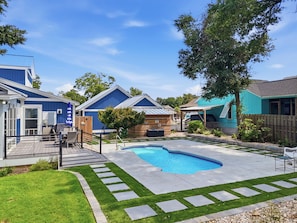 Un jardin à l’arrière d’une maison, avec une piscine, une terrasse en bois et une zone délimitée par une clôture.