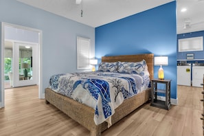 Une chambre à coucher avec un lit, une table de chevet, une lampe et une vue sur l’extérieur.