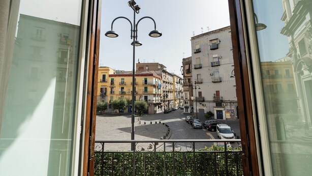 A view of a city street from a window, including buildings, a street lamp, and parked cars.